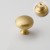 Nahaufnahme der abgerundeten Form und der glatten Oberfläche in gebürstetem Gold des Messing-Möbelknopfes für Schränke.