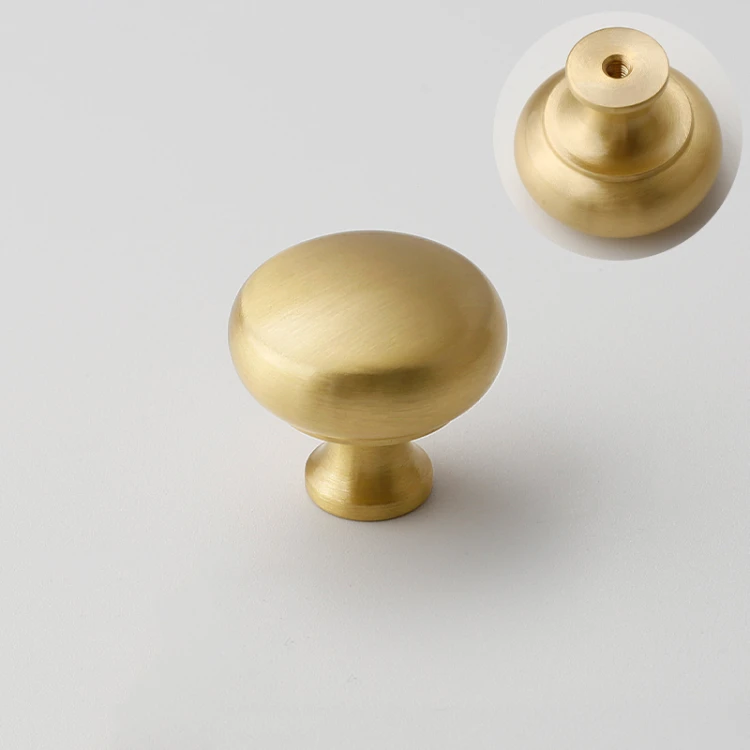 Nahaufnahme der abgerundeten Form und der glatten Oberfläche in gebürstetem Gold des Messing-Möbelknopfes für Schränke.