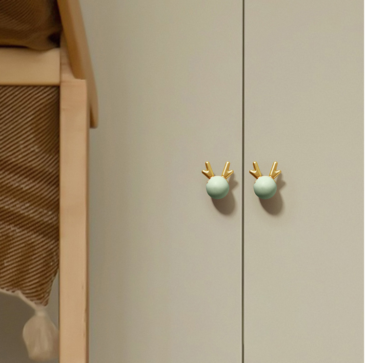 Kindermöbelgriff Deer – pastellfarbene Kugel mit dekorativem goldenem Geweih. Farben: Rosa, Grün, Hellblau und Weiß. Ideal für Schubladen, Kommoden und Schränke in märchenhaften, skandinavischen Kinderzimmern.