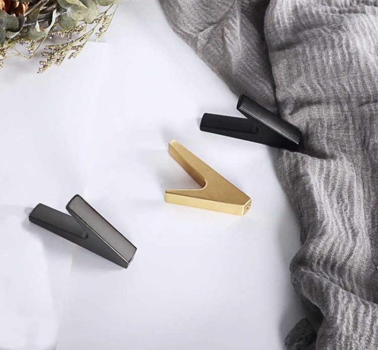 Wandhaken Bola – minimalistischer geometrischer Haken für Zuhause, Büro und Hotels. Aus robustem Metall, einfache Montage mit Schrauben im Set. Farben: Schwarz, Perlgrau und gebürstetes Gold.